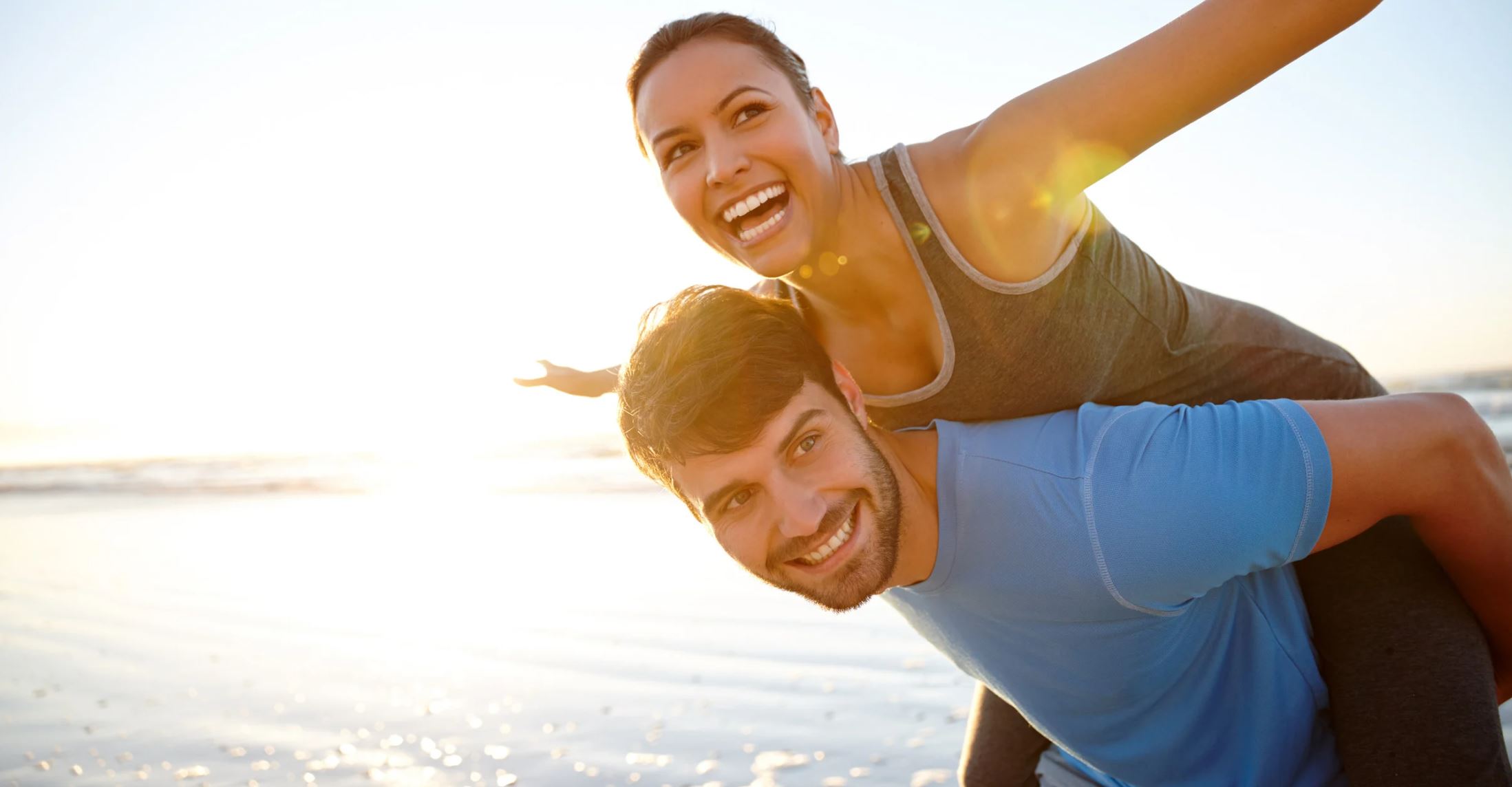 Lachendes Paar am Strand bei Sonnenlicht – Symbol für Lebensfreude, Energie und Vitalität mit Smiling Wisdom